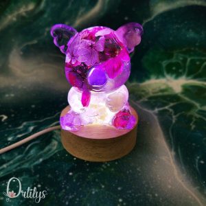 Un koala rempli de fleurs violettes et blanches, la veilleuse est allumée